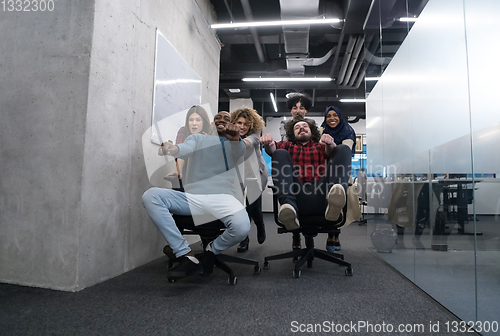 Image of multiethnics business team racing on office chairs