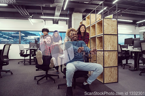 Image of multiethnics business team racing on office chairs