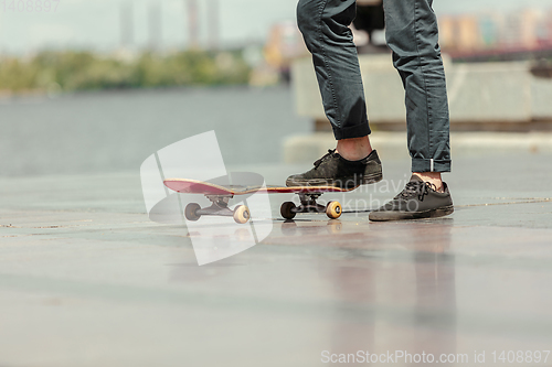 Image of Skateboarder doing a trick at the city\'s street in sunny day