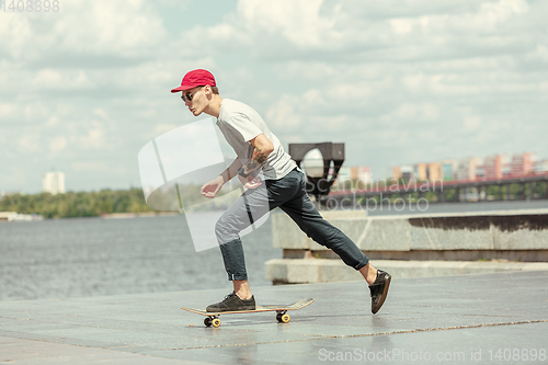 Image of Skateboarder doing a trick at the city\'s street in sunny day