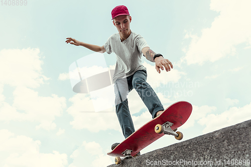 Image of Skateboarder doing a trick at the city\'s street in sunny day