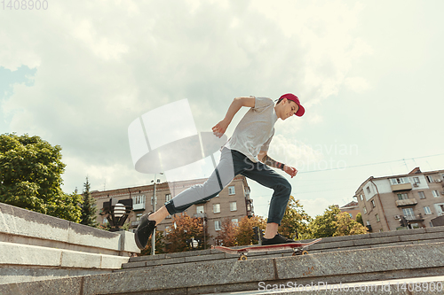 Image of Skateboarder doing a trick at the city\'s street in sunny day