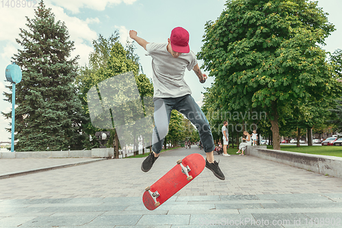 Image of Skateboarder doing a trick at the city\'s street in sunny day