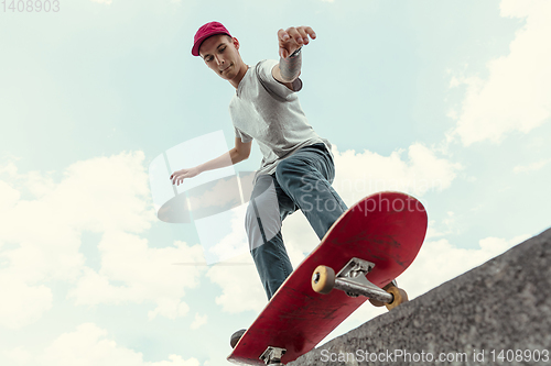 Image of Skateboarder doing a trick at the city\'s street in sunny day