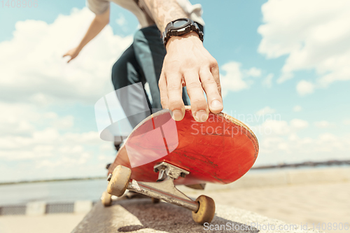 Image of Skateboarder doing a trick at the city\'s street in sunny day