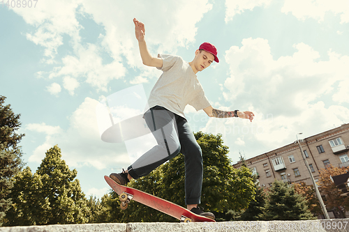 Image of Skateboarder doing a trick at the city\'s street in sunny day