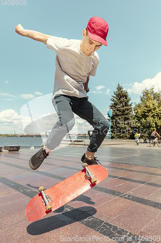 Image of Skateboarder doing a trick at the city\'s street in sunny day