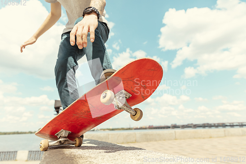 Image of Skateboarder doing a trick at the city\'s street in sunny day