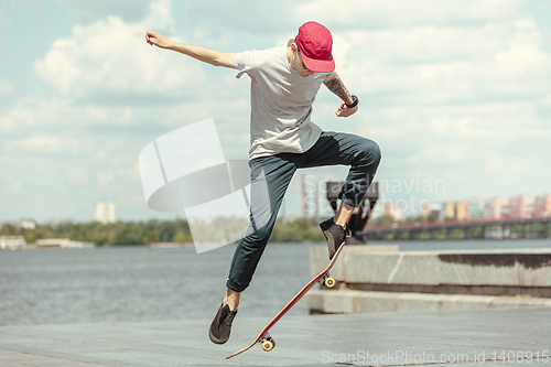 Image of Skateboarder doing a trick at the city\'s street in sunny day