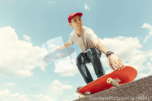 Image of Skateboarder doing a trick at the city\'s street in sunny day