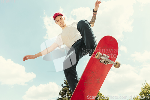 Image of Skateboarder doing a trick at the city\'s street in sunny day