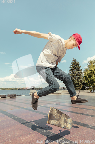 Image of Skateboarder doing a trick at the city\'s street in sunny day