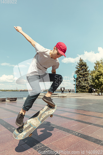 Image of Skateboarder doing a trick at the city\'s street in sunny day