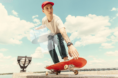 Image of Skateboarder doing a trick at the city\'s street in sunny day