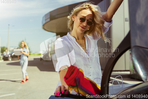 Image of Young lesbian\'s couple preparing for vacation trip on the car in sunny day