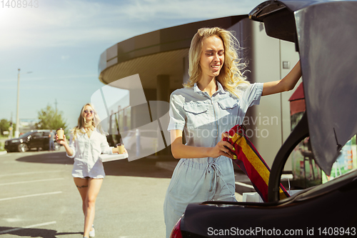 Image of Young lesbian\'s couple preparing for vacation trip on the car in sunny day