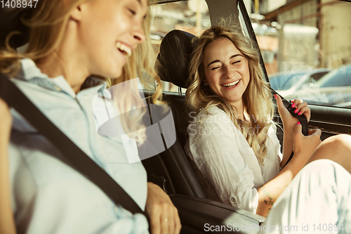 Image of Young lesbian\'s couple preparing for vacation trip on the car in sunny day