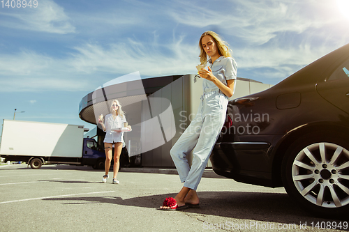 Image of Young lesbian\'s couple preparing for vacation trip on the car in sunny day