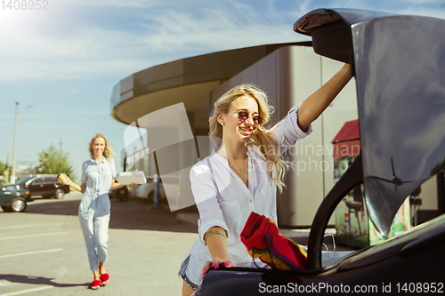 Image of Young lesbian\'s couple preparing for vacation trip on the car in sunny day