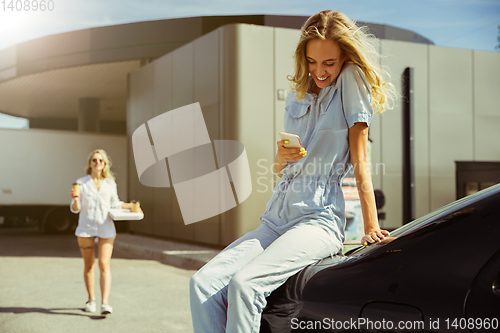 Image of Young lesbian\'s couple preparing for vacation trip on the car in sunny day
