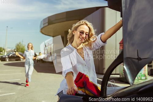 Image of Young lesbian\'s couple preparing for vacation trip on the car in sunny day
