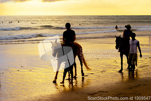 Image of tourists riding horses on beach