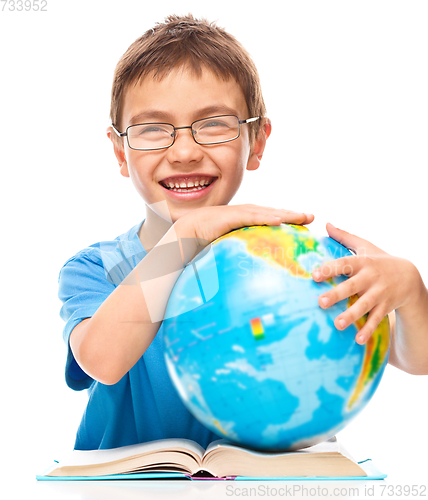 Image of Little boy is examining globe