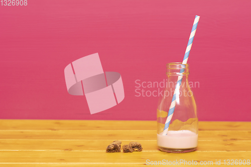 Image of Straw and half bottle of strawberry milkshake with cookie crumbs