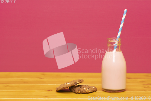 Image of Strawberry milkshake and straw in a bottle with a cookie