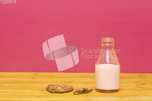 Image of Milk bottle half full of strawberry milkshake with half-eaten co