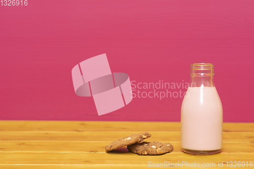Image of Strawberry milkshake in a glass milk bottle with a cookie