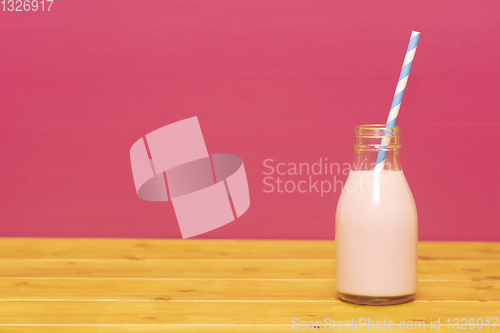 Image of Strawberry milkshake with a straw in a glass milk bottle