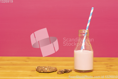 Image of Half bottle of strawberry milkshake with straw and half-eaten co