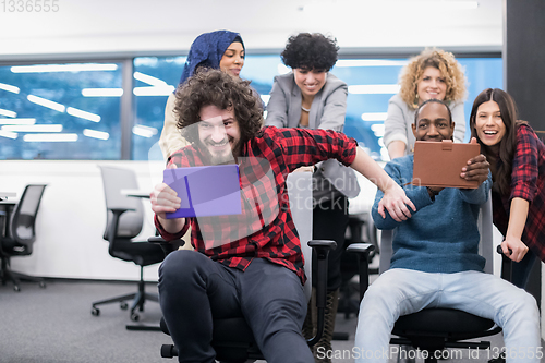 Image of multiethnics business team racing on office chairs