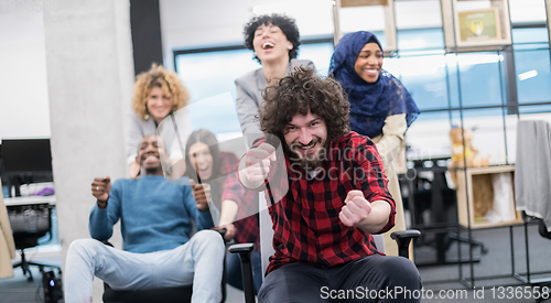 Image of multiethnics business team racing on office chairs