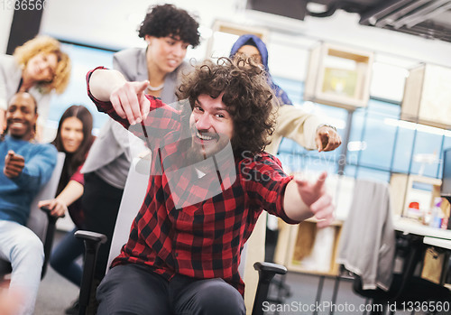 Image of multiethnics business team racing on office chairs