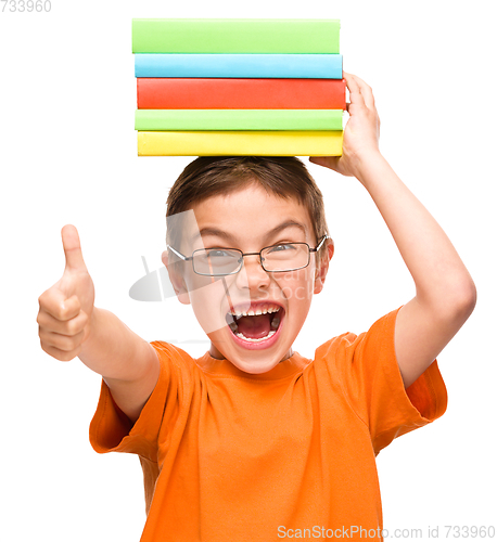 Image of Little boy is holding a pile of books