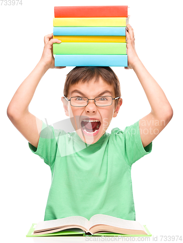 Image of Little boy is holding a pile of books