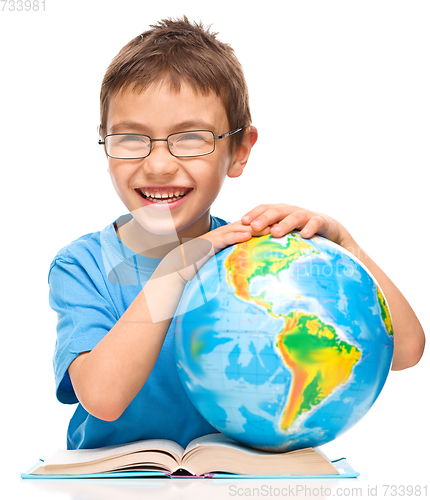 Image of Little boy is examining globe