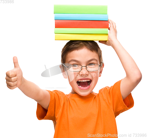 Image of Little boy is holding a pile of books