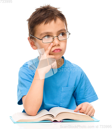 Image of Young boy is daydreaming while reading book