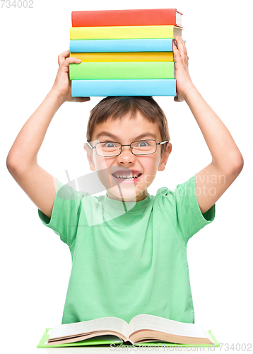 Image of Little boy is holding a pile of books