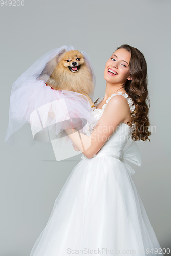 Image of beautiful bride girl with spitz bride on gray background