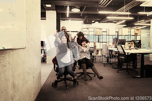 Image of multiethnics business team racing on office chairs