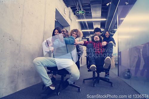 Image of multiethnics business team racing on office chairs