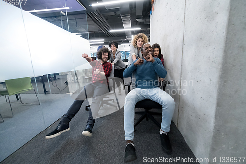 Image of multiethnics business team racing on office chairs