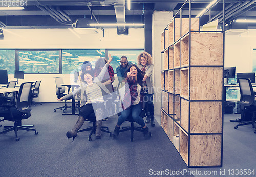 Image of multiethnics business team racing on office chairs