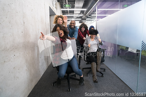 Image of multiethnics business team racing on office chairs