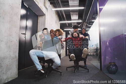 Image of multiethnics business team racing on office chairs