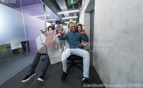 Image of multiethnics business team racing on office chairs